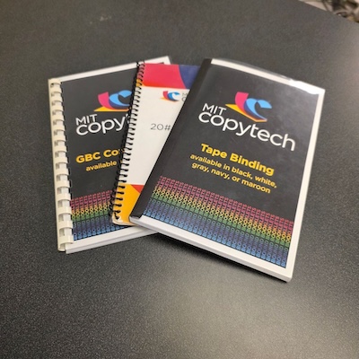 Three bound booklets show examples of plastic comb binding, spiral plastic coil, and adhesive tape binding.