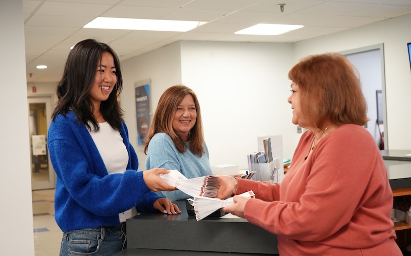 Two customers talk with a Copytech staff member behind the front counter.